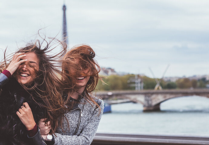 Zwei junge Frauen auf einer Brücke in Paris.