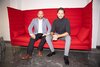 Robin Stöckli und ein Dozent sitzen auf einem roten Sofa