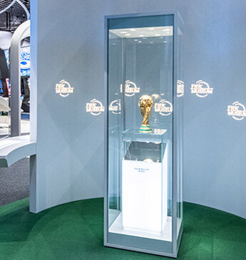 In der Ausstellungshalle des FIFA Museums in Zürich ist eine gläserne Vitrine zentral platziert, in der die funkelnde FIFA-Weltmeisterschaftstrophäe präsentiert wird, umgeben von interaktiven Displays und Fußballerinnerungsstücken, die die reiche Geschichte und die globale Liebe zum Fußball verdeutlichen.
