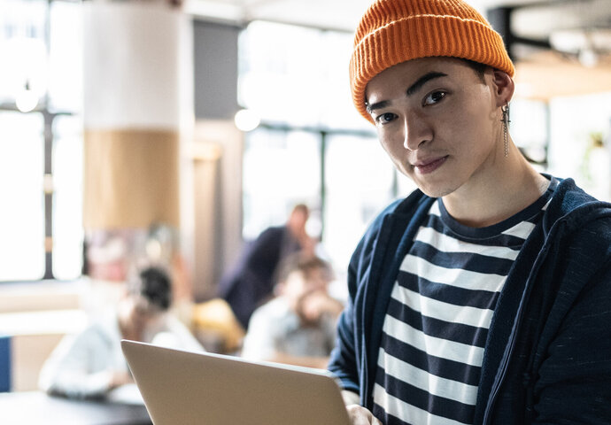 Junger Informatiker mit Laptop in der Hand.