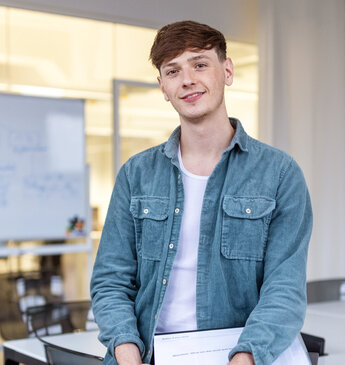 Junger Kaufmann steht in einem modernen Büro.